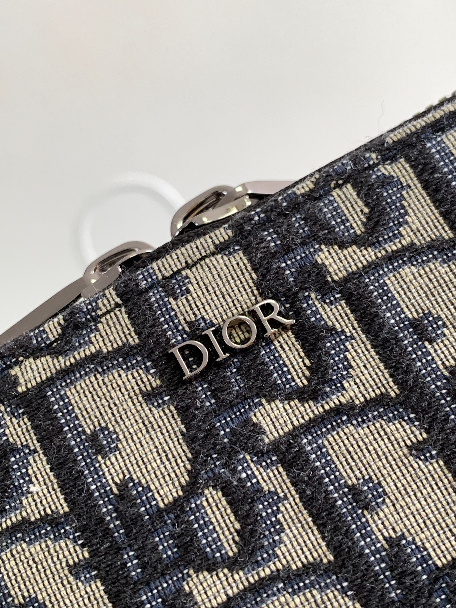 Dior pattern bag fabric close-up with “Dior” lettering on woven navy and beige material