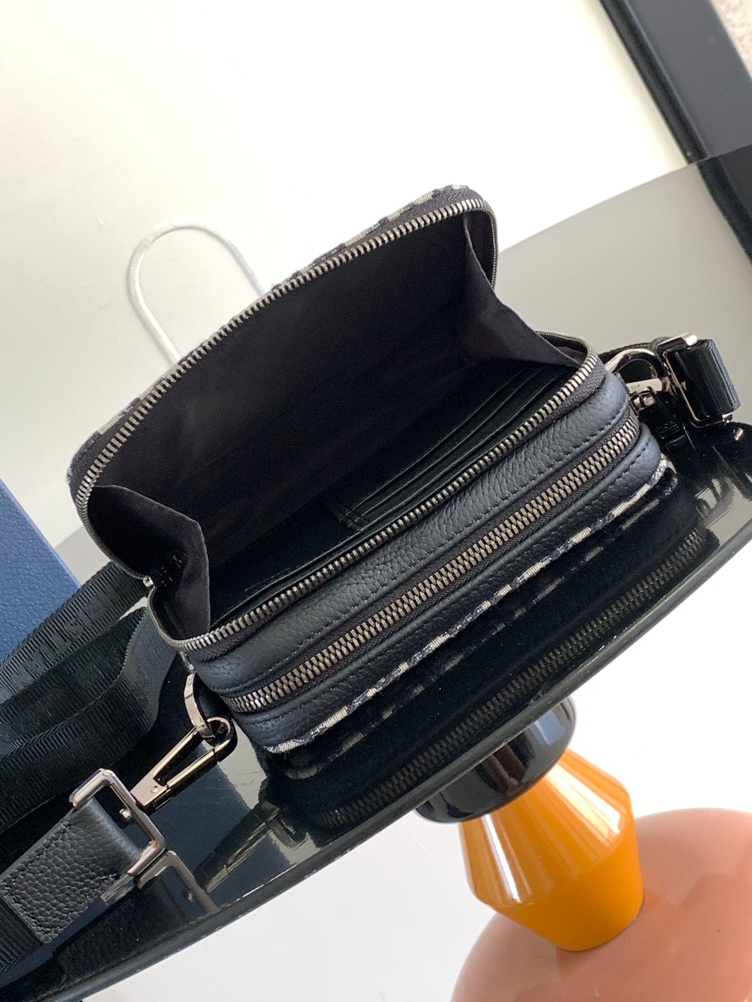 Crossbody bag interior view with black lining and dual zip compartments on patterned exterior