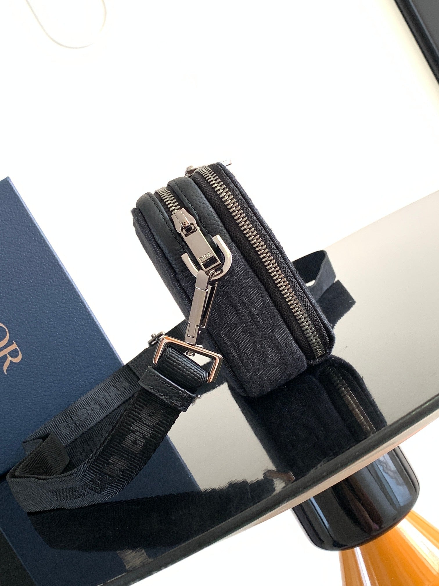 Dior bag dark navy monogram canvas with metal zipper pull and adjustable shoulder strap