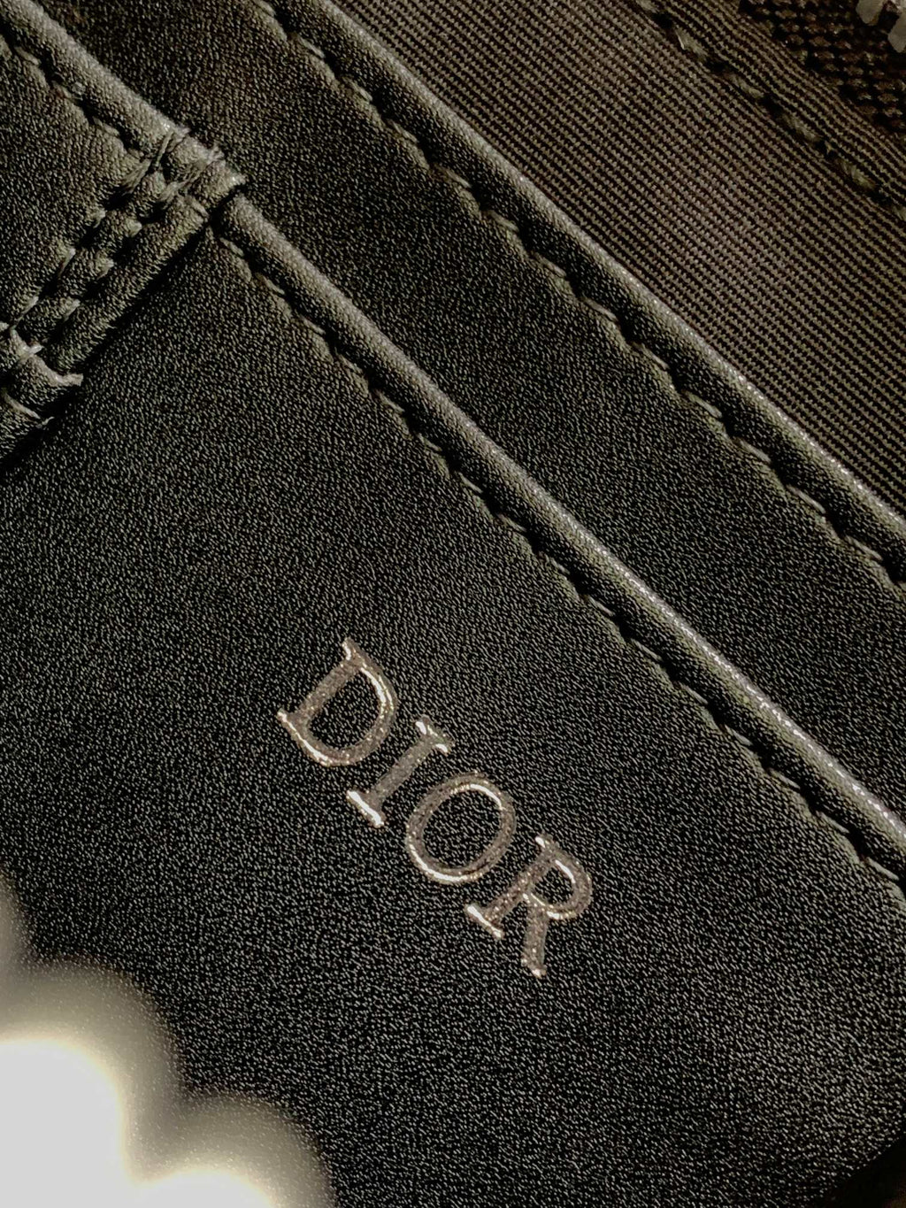 Dior bag dark navy textured surface with engraved DIOR logo lettering