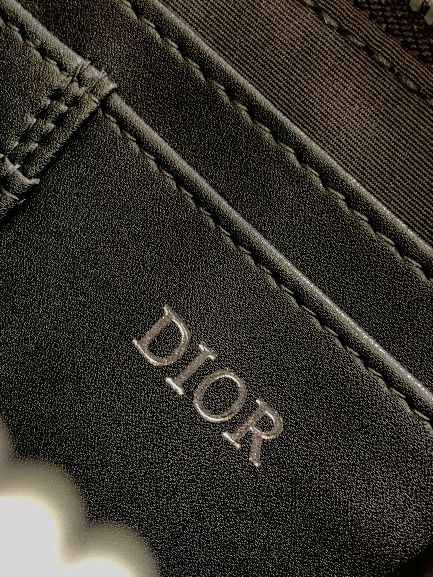 Dior bag dark navy textured surface with engraved DIOR logo lettering