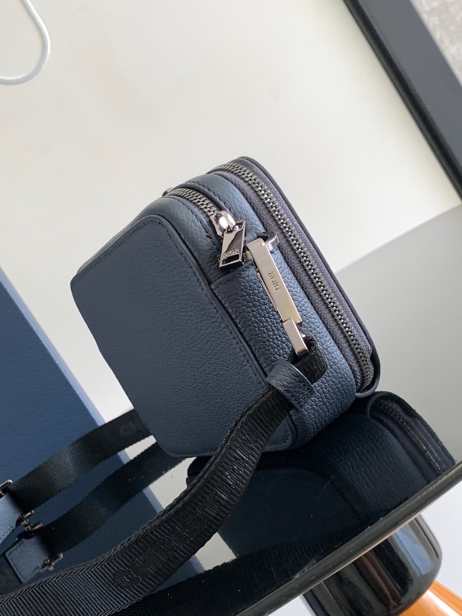 Navy leather crossbody bag with silver zipper, structured front panel, adjustable strap