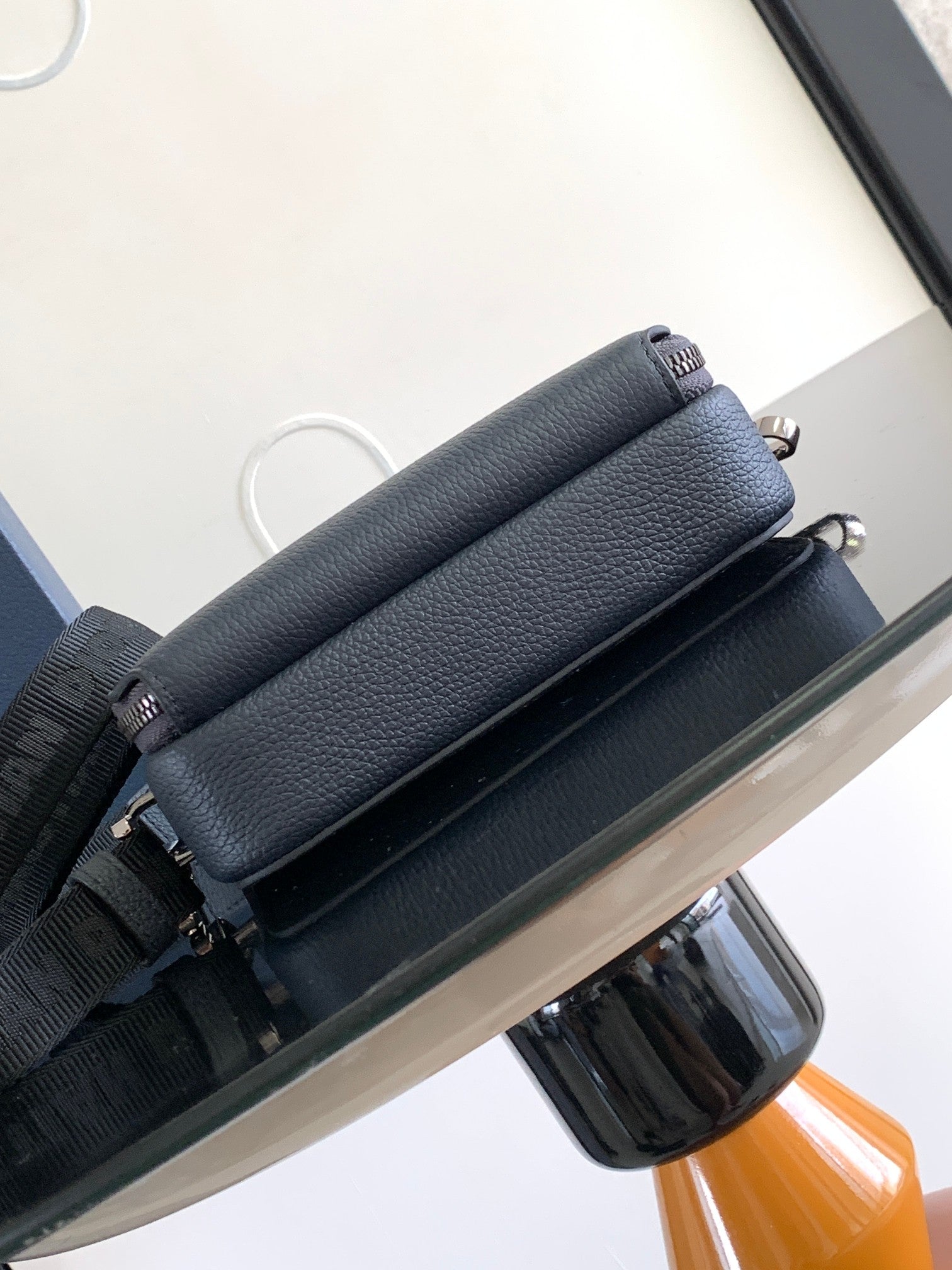 Navy leather crossbody bag with wide strap and top zipper, shown from the side