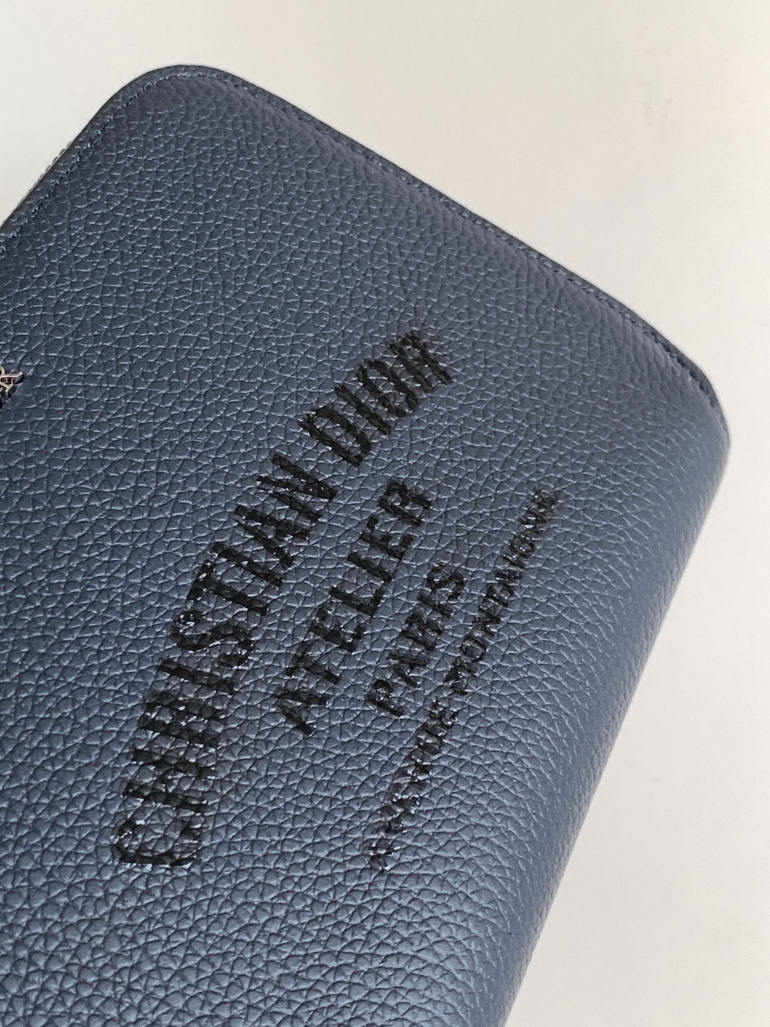 Blue textured leather bag with embossed black Dior logo on the front panel