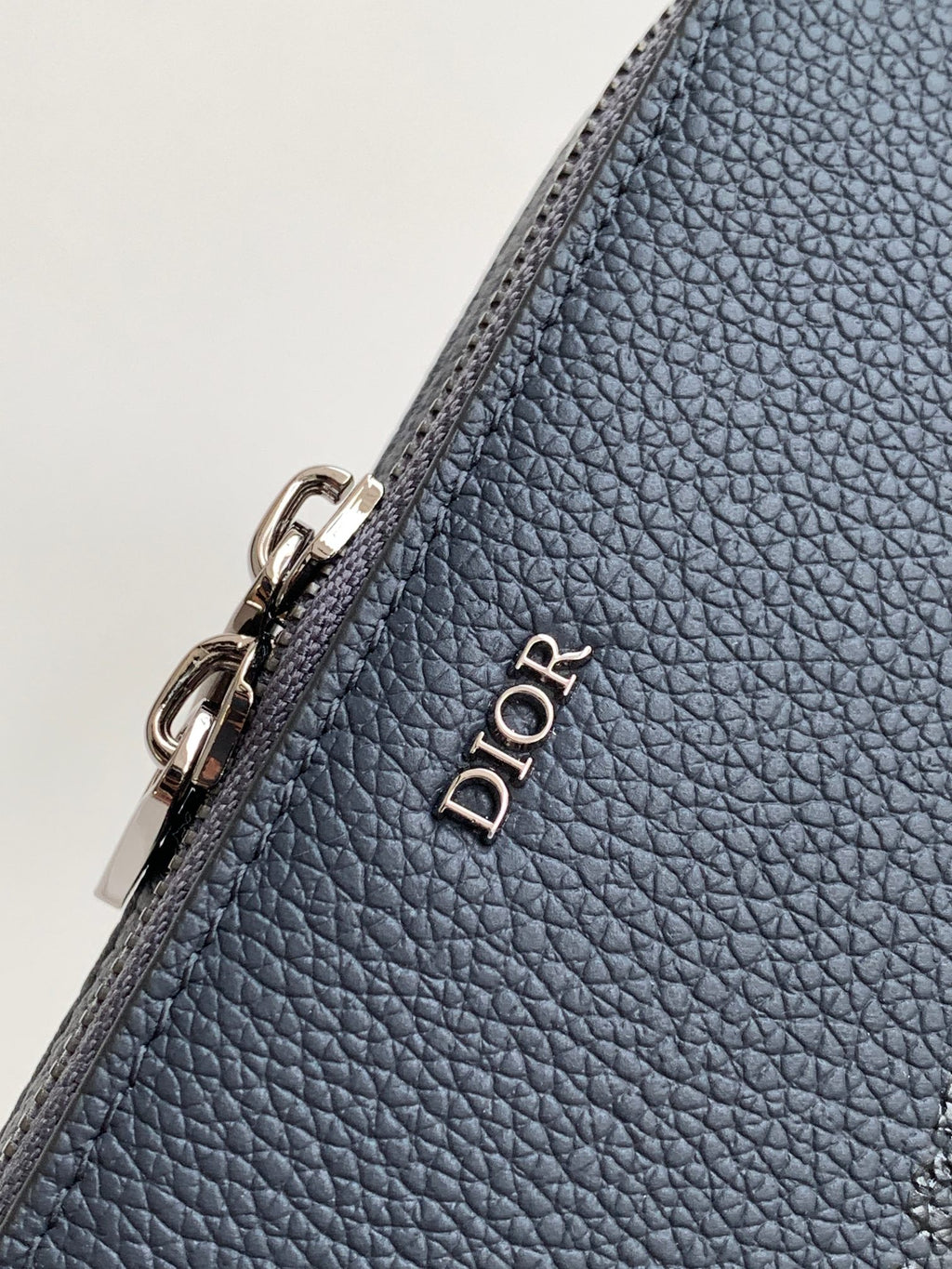 Blue textured leather bag corner with silver zipper hardware and Dior wordmark