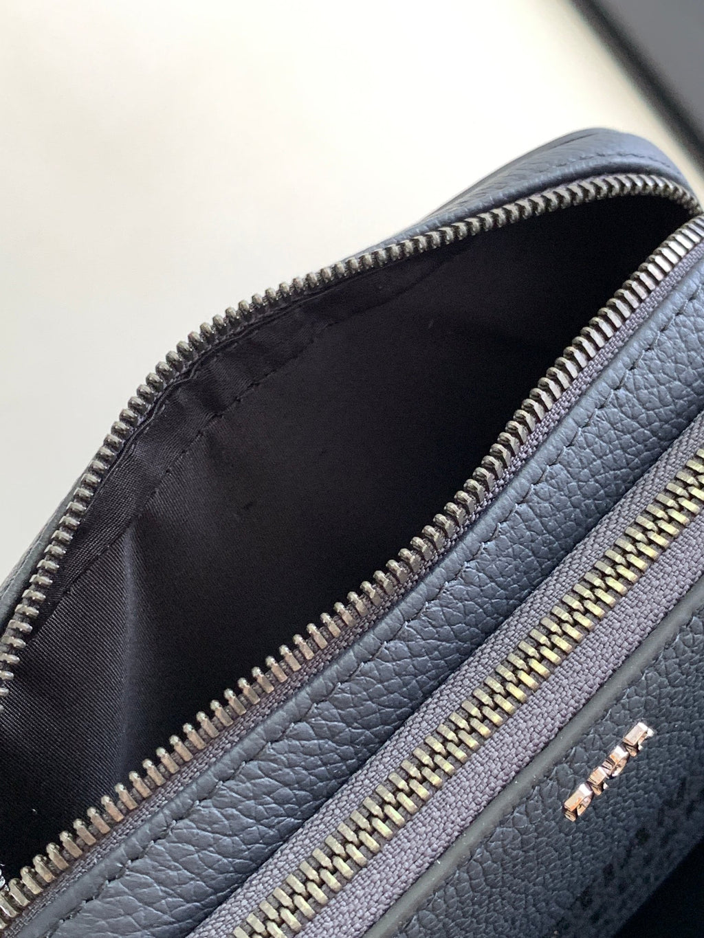 Blue leather crossbody bag opening with black lining and gold-tone zipper
