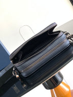 Navy leather crossbody bag with open top, black lining, and two gold-tone zippers