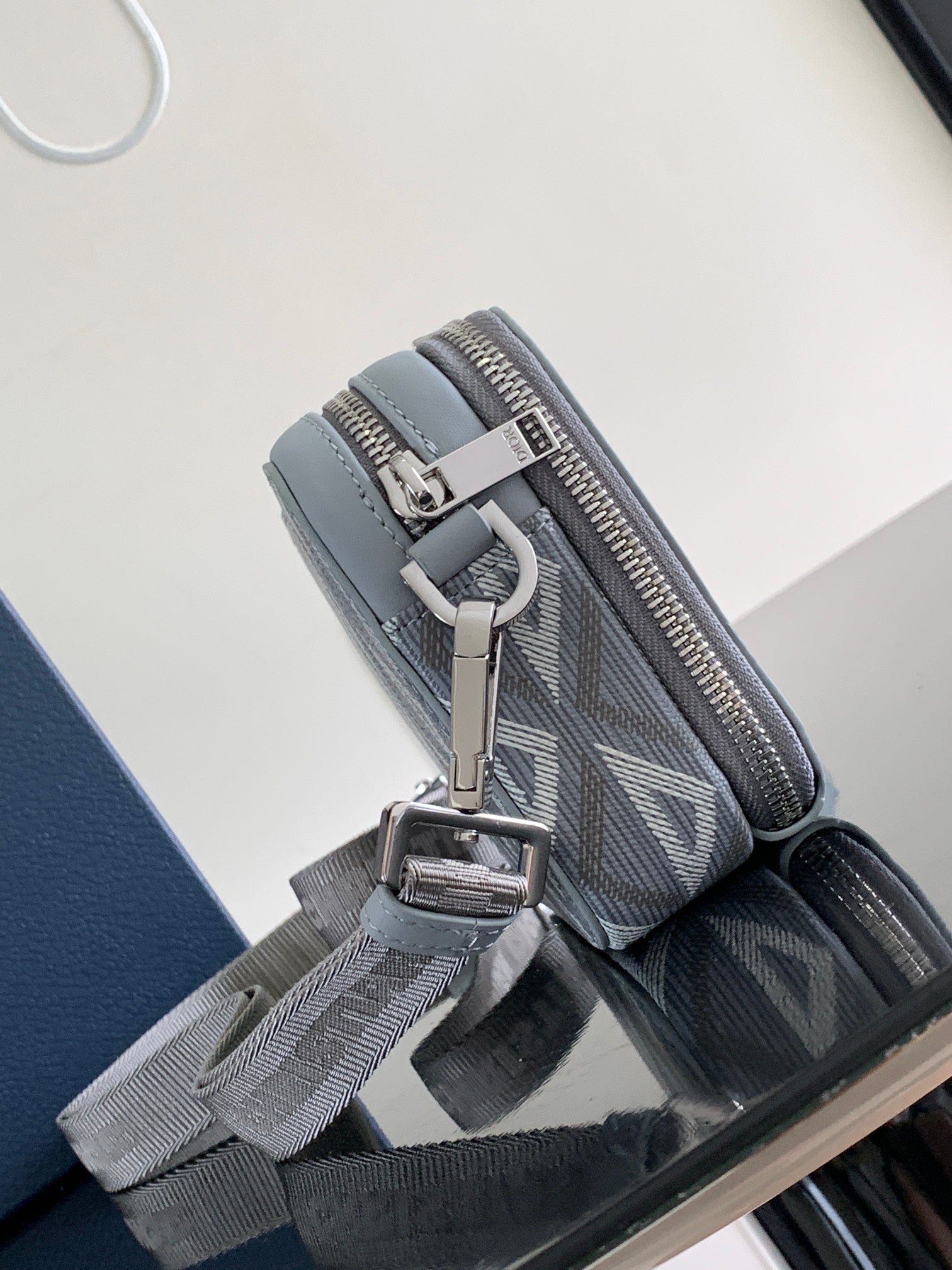 Dior mini bag side view with zip, light blue trim, and adjustable crossbody strap
