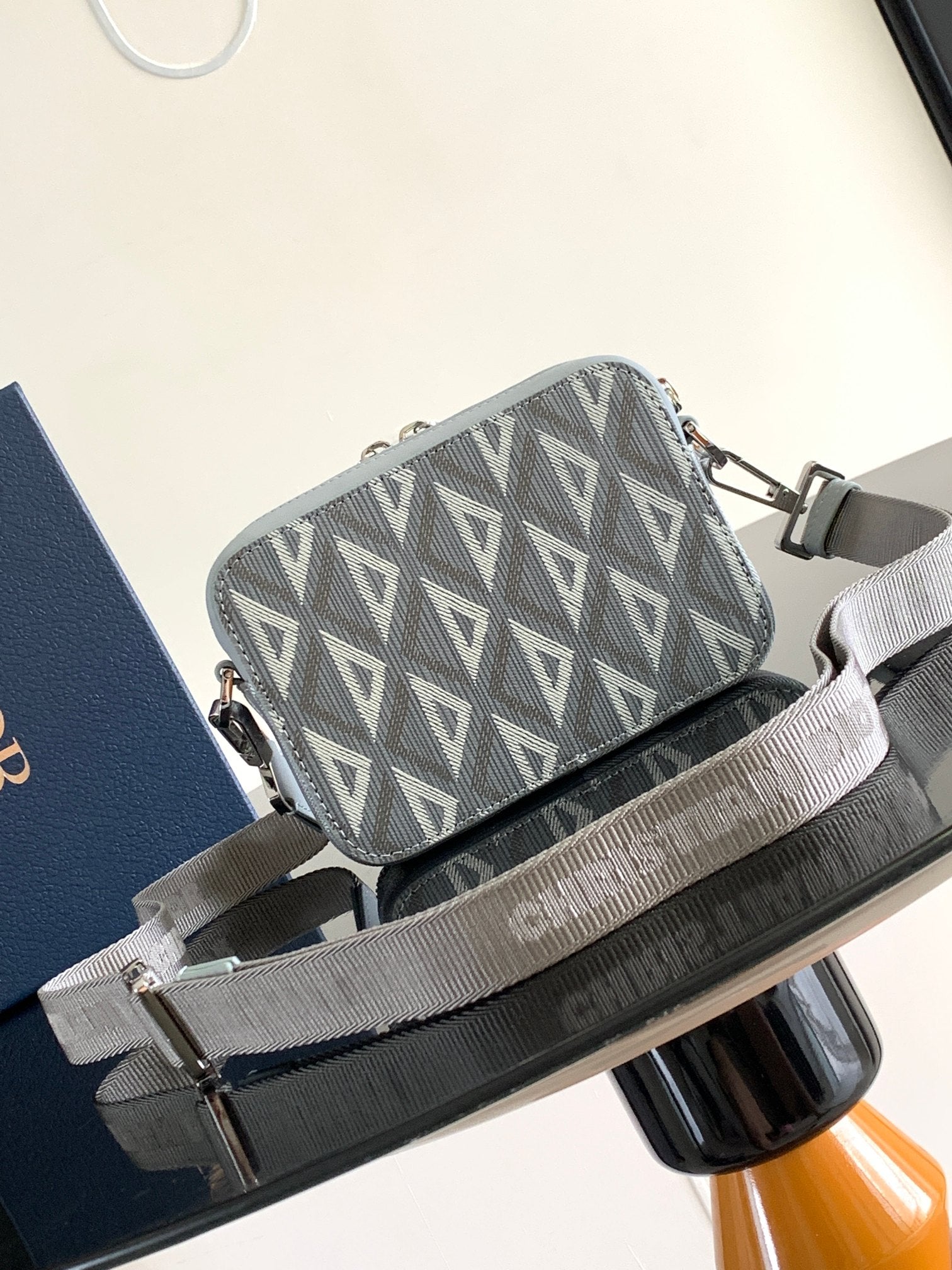 Dior mini crossbody bag with gray Dior Oblique pattern, light blue leather trim, and zip top