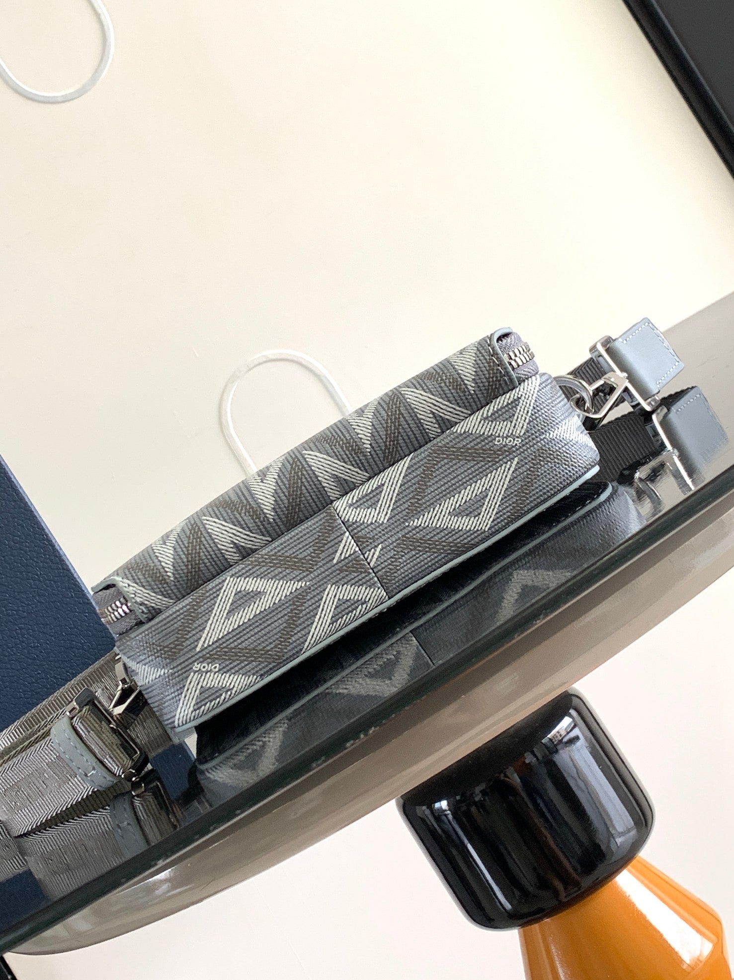 Dior mini bag front view with gray Dior Oblique pattern and light blue strap hardware