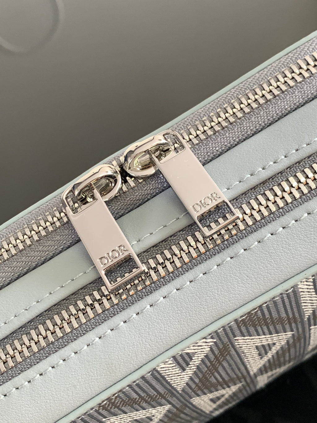 Dior mini bag close-up: light blue leather panel with silver zippers and stitched details
