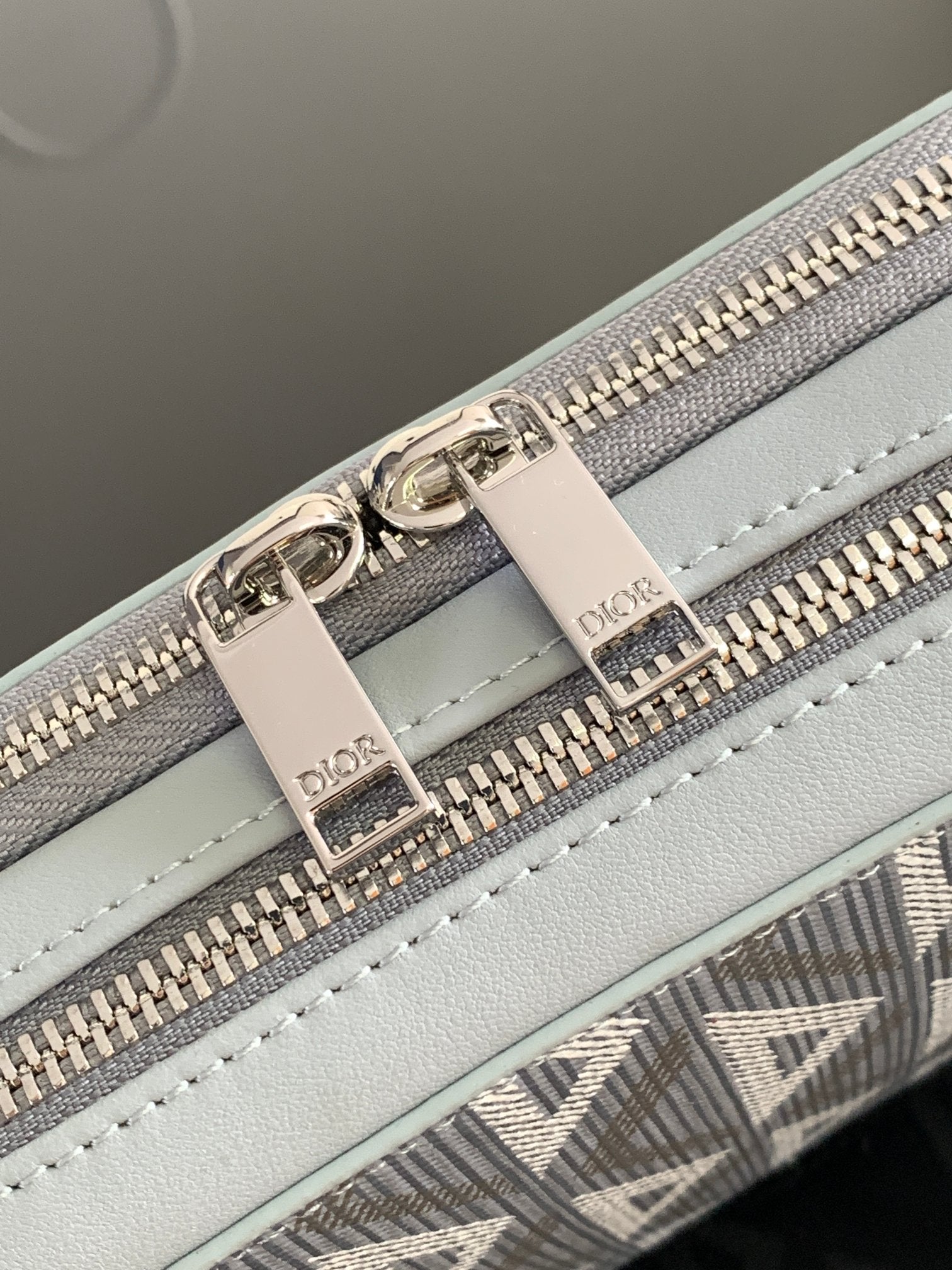 Dior mini bag close-up: light blue leather panel with silver zippers and stitched details