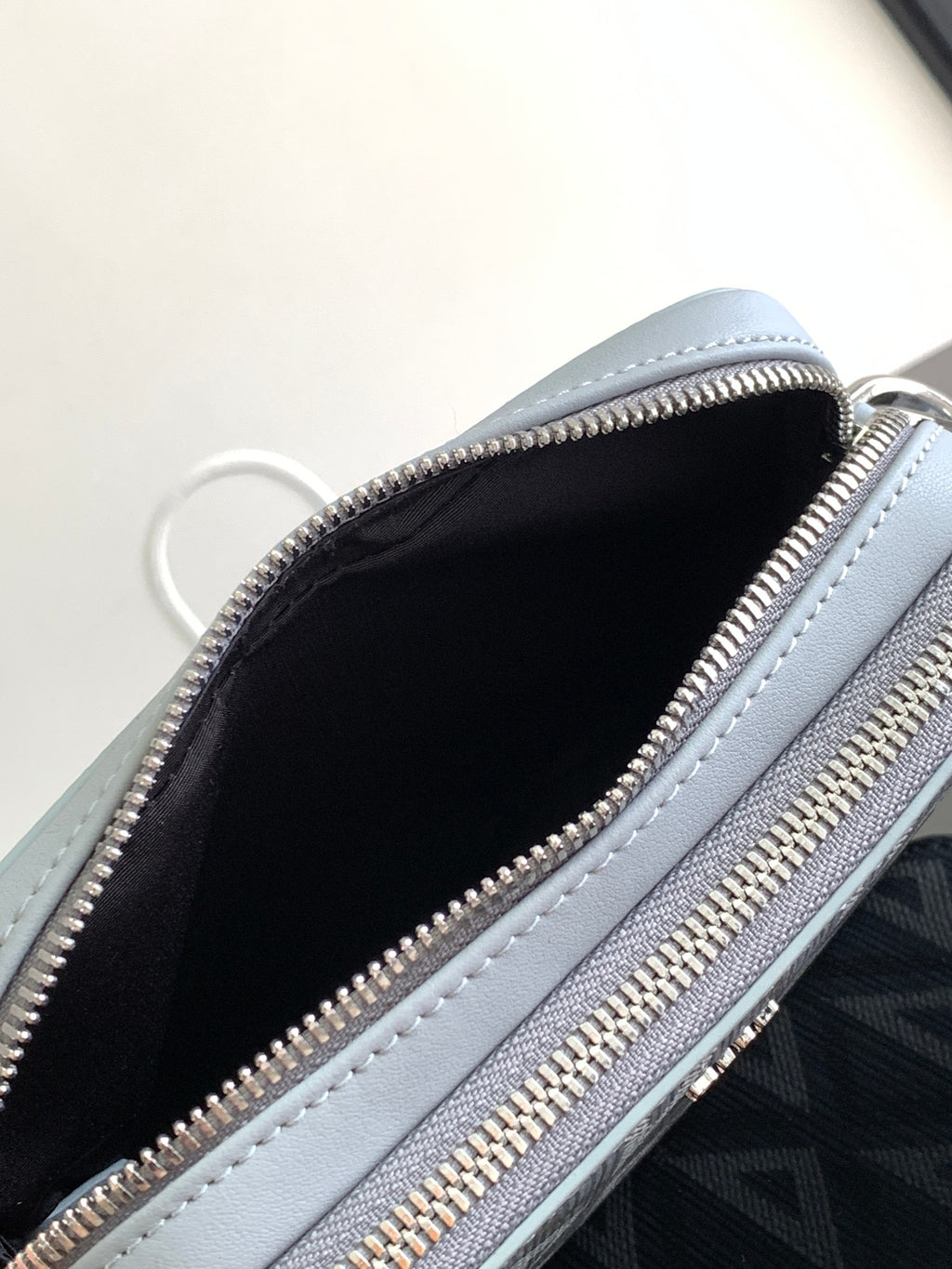 Dior mini bag interior view with zip opening and black lining, light blue leather edges