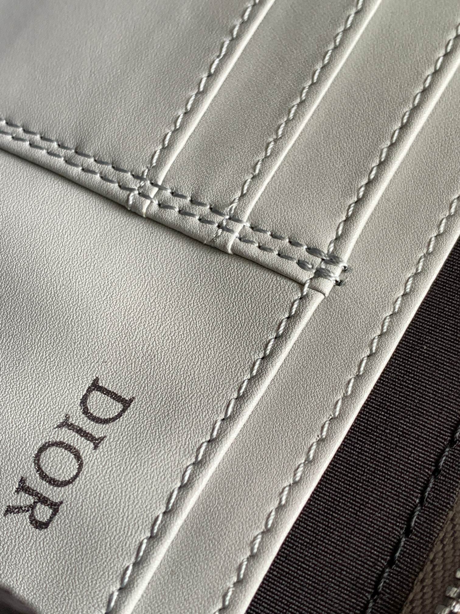 Dior mini bag leather close-up with stitched seams and embossed Dior logo