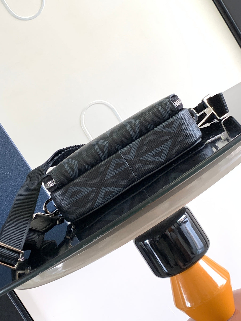 Dark monogram crossbody bag with front straps and silver-tone buckles