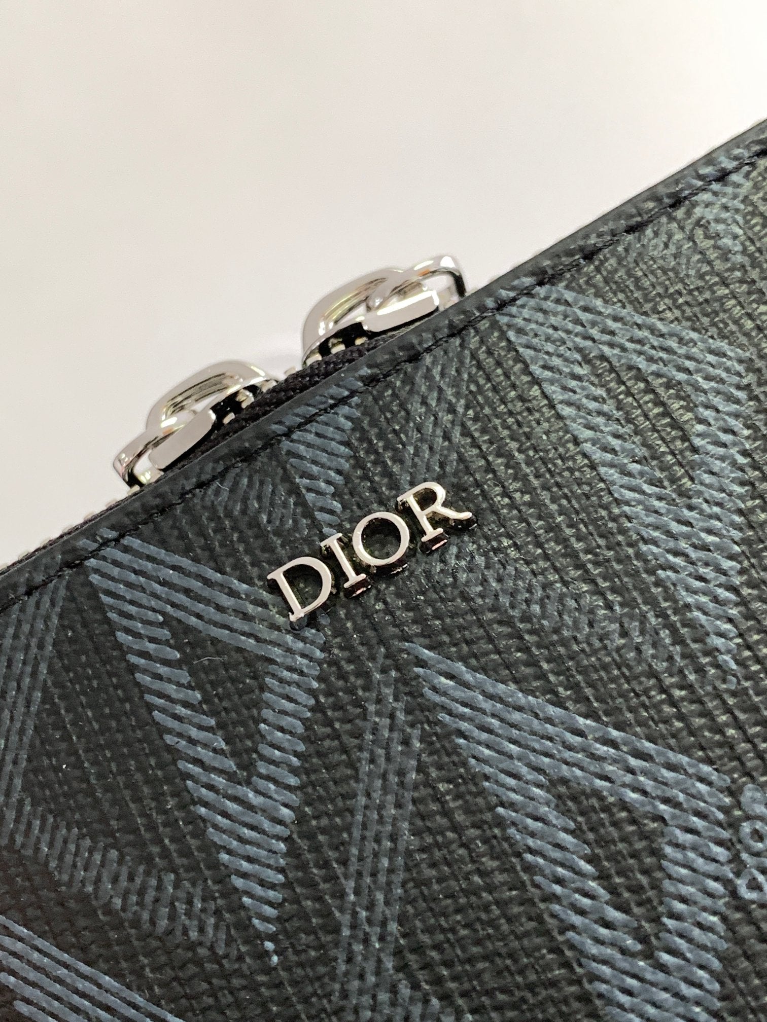 Dark patterned bag with Dior logo on textured leather and stitched edge
