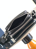 Black double-zip crossbody bag with front zipper compartments and metal clasp