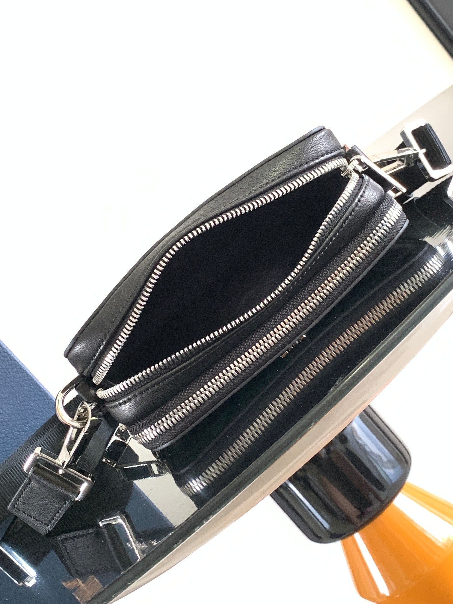 Black double-zip crossbody bag with front zipper compartments and metal clasp