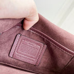 Coah Bags interior label patch on maroon suede lining, stitched rectangular tag.