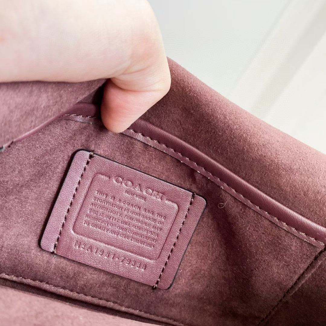 Coah Bags interior label patch on maroon suede lining, stitched rectangular tag.