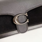 Coah bag close-up of silver O-ring clasp and flap edge stitching, black textured exterior