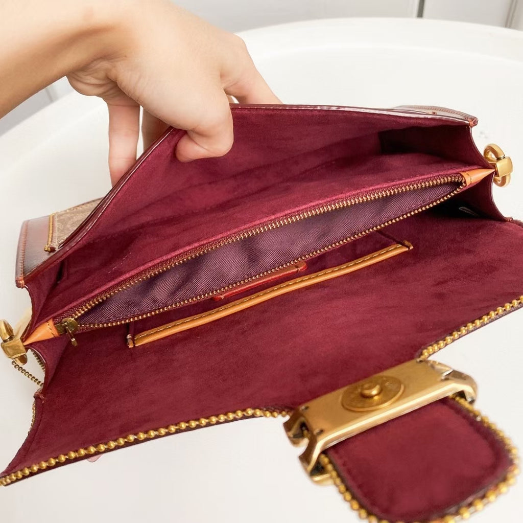 Coah bag open view showing burgundy suede interior and gold-tone zipper