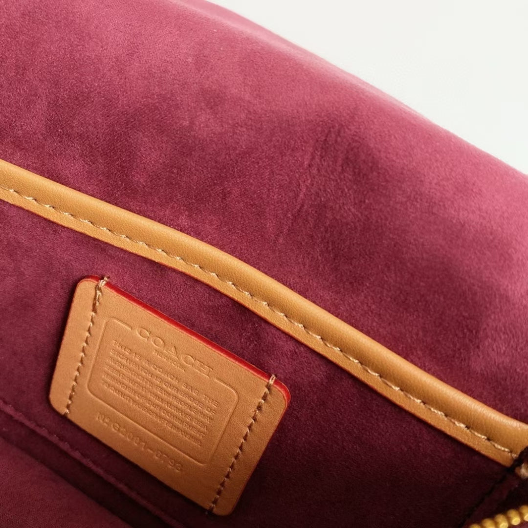 Coah bag label patch on burgundy suede interior with gold trim