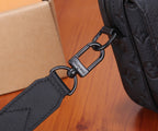 Close-up of dark crossbody bag strap with metal rings and branded connector