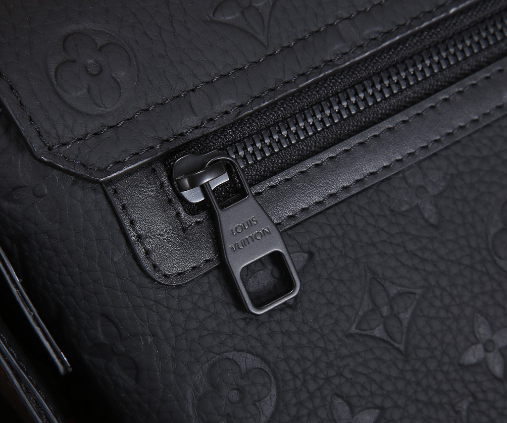 Dark monogram bag zipper pull with metal clasp and stitched leather trim