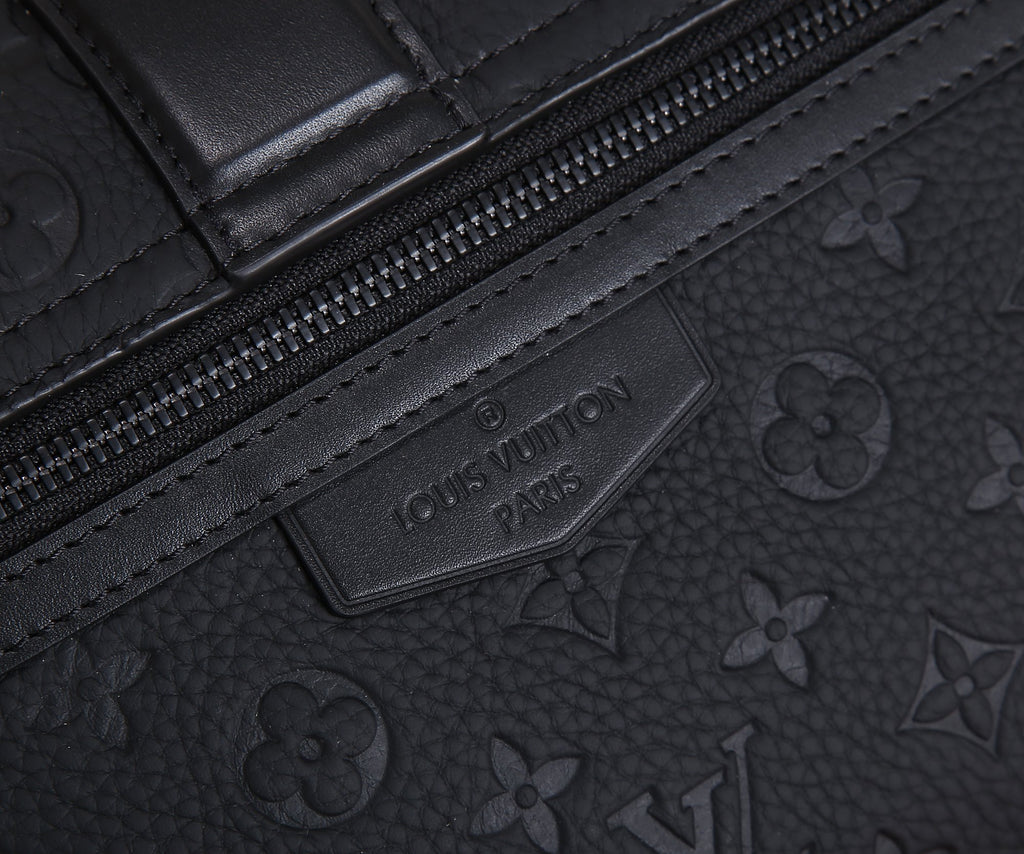Louis Vuitton monogram bag close-up of embossed label on leather trim, dark