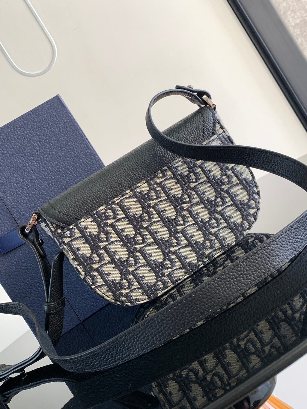 Dior mini bag with black pebbled leather base and blue-and-beige monogram canvas body
