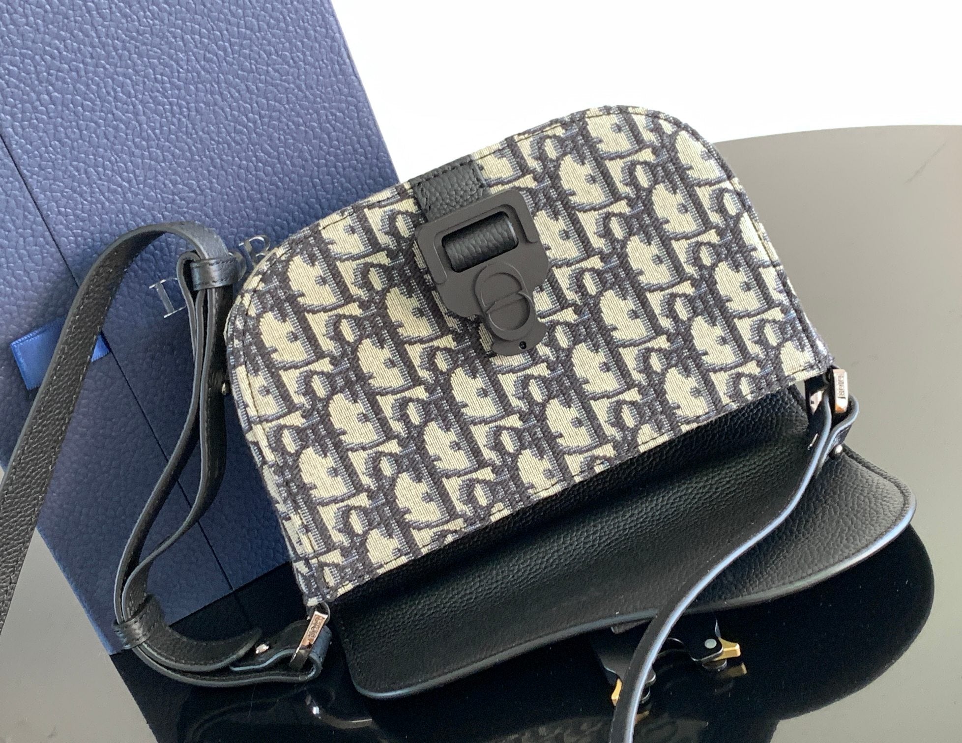 Dior mini bag with blue-and-beige monogram canvas flap and black leather shoulder strap