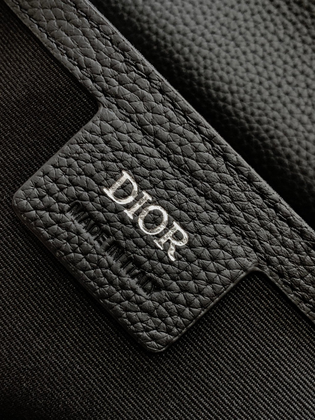 Dior leather patch with debossed 'Dior' logo on textured black grain