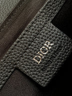 Dior bag detail, black leather patch with Dior logo and stitched strap edge