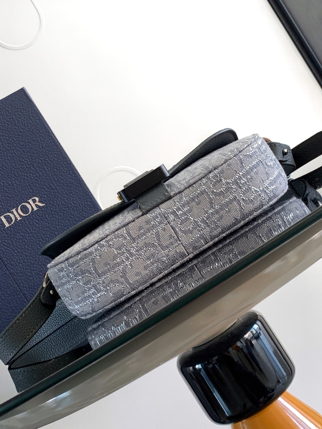 Dior gray patterned baguette-style bag with top handle and front buckle hardware.