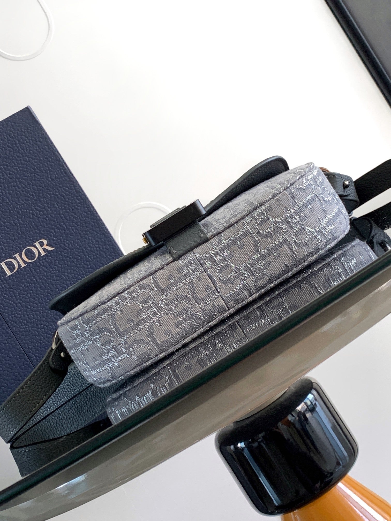 Dior gray patterned baguette-style bag with top handle and front buckle hardware.