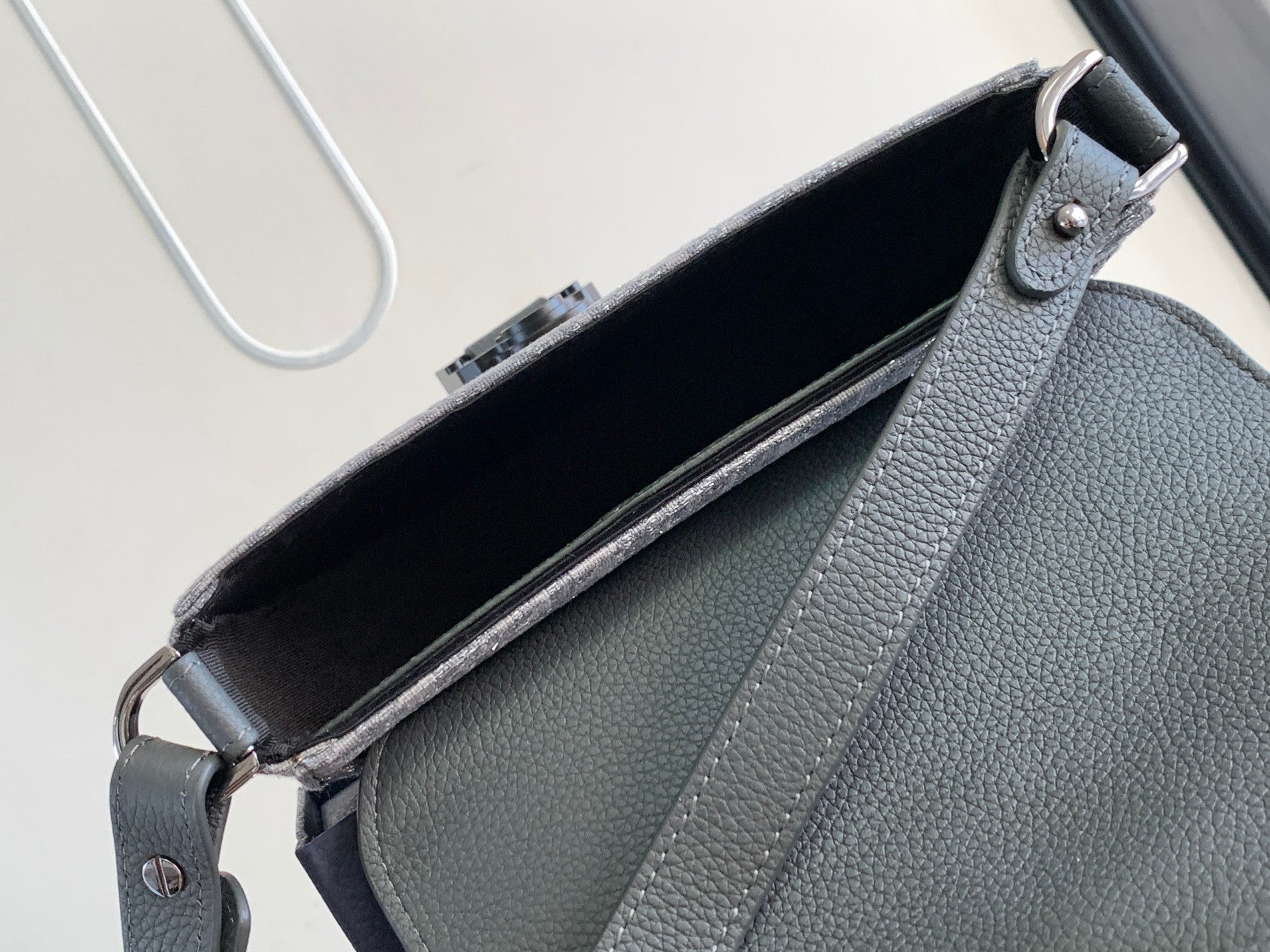 Dior gray leather bag interior view with top flap opening and side seam detail.