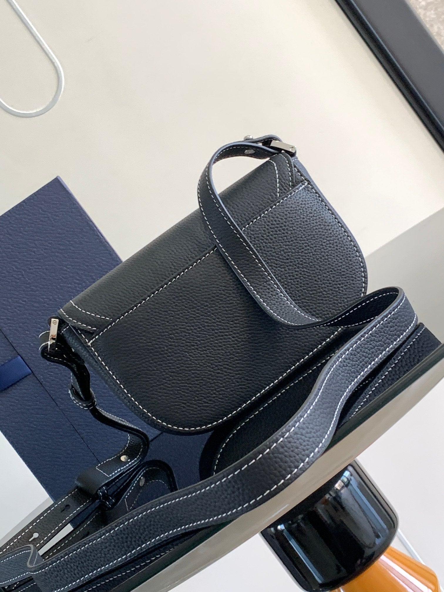 Navy leather Dior shoulder bag with stitched flap, top handle, and long crossbody strap