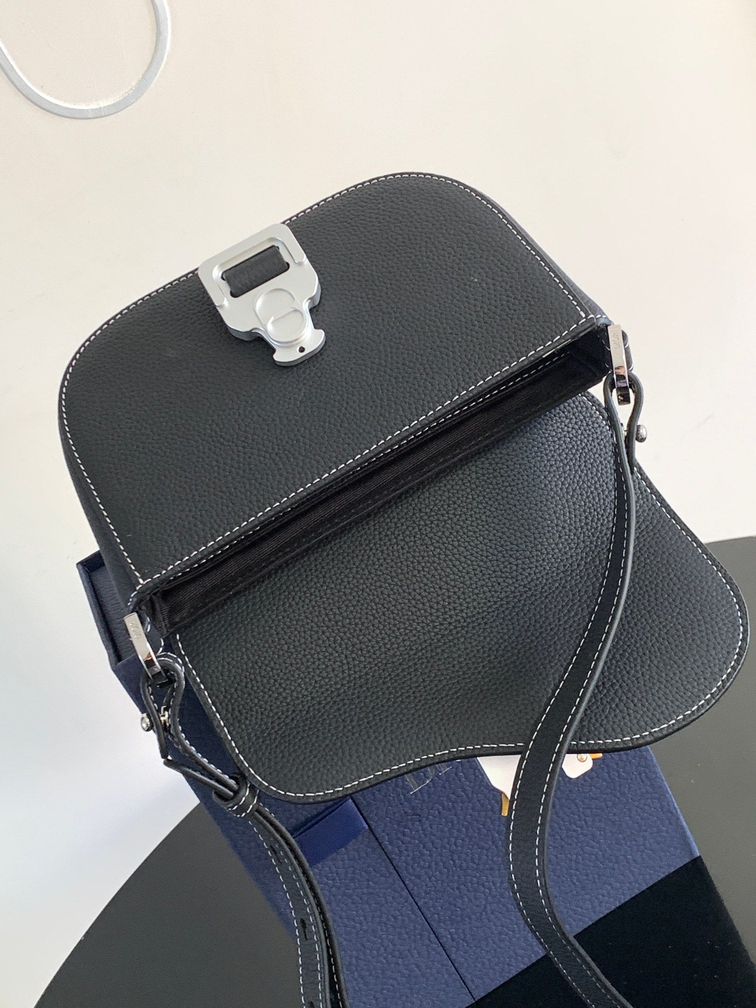 Dark leather Dior small bag with flap top, side zip, and long shoulder strap