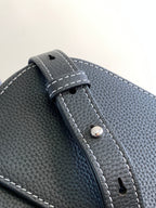 Textured dark leather Dior bag strap detail with stitched edge and metal rivet