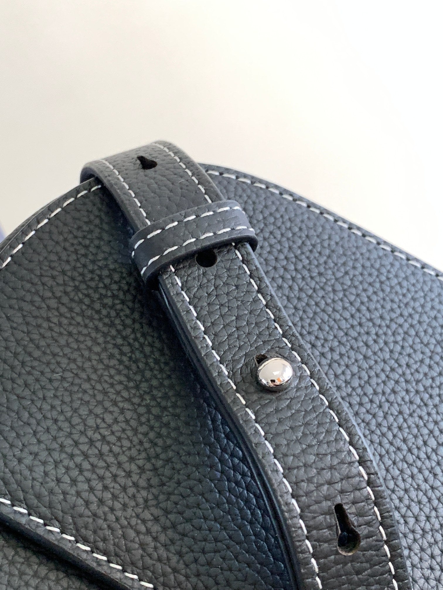 Textured dark leather Dior bag strap detail with stitched edge and metal rivet