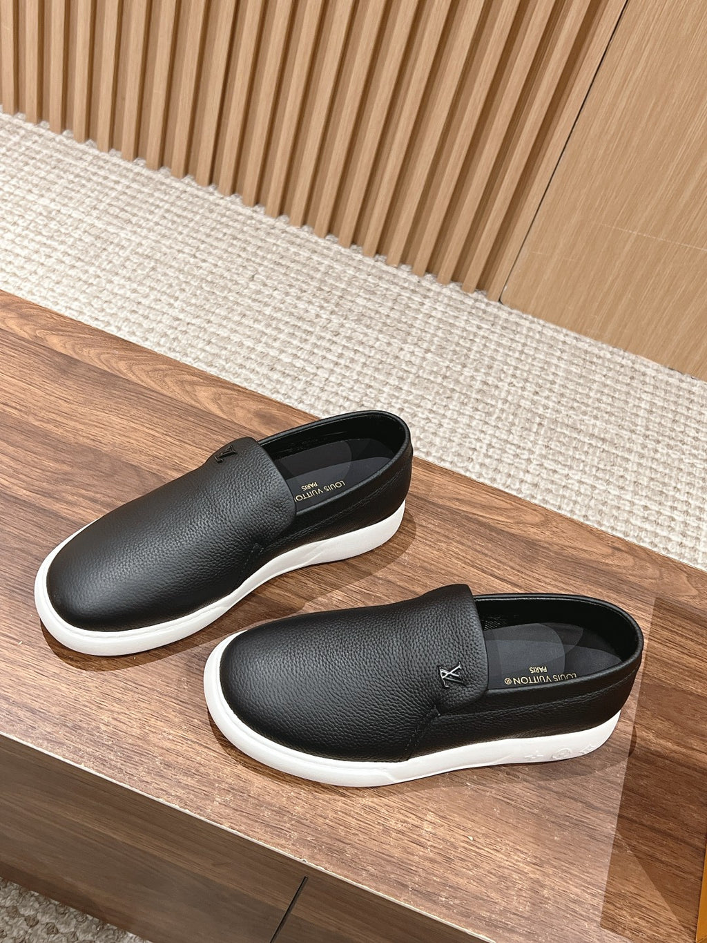 Black leather slip-on sneakers, side and back view with white soles
