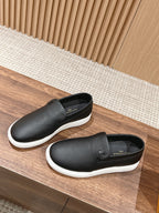 Black leather slip-on sneakers, side and back view with white soles