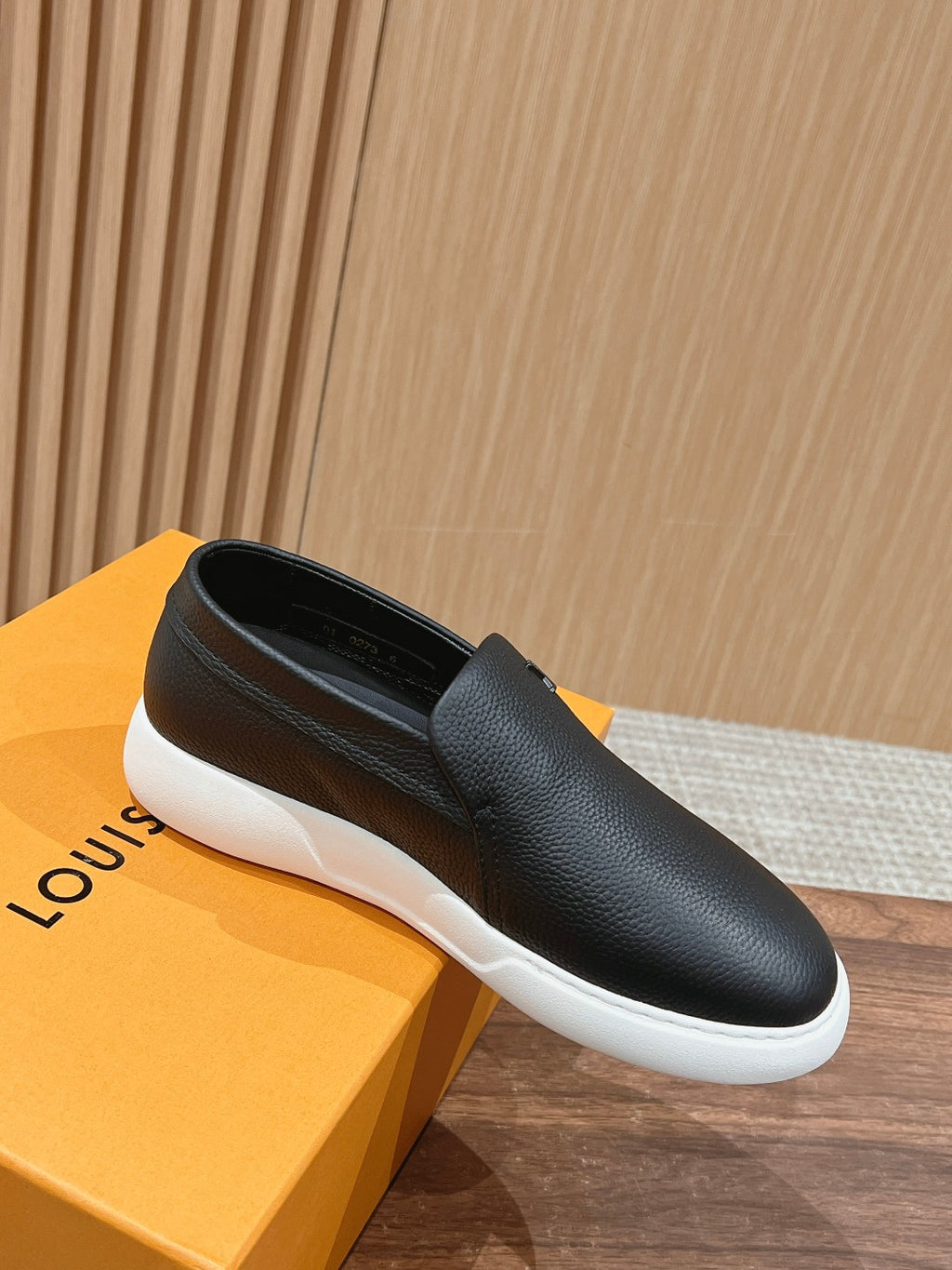 Black leather slip-on sneakers with white rubber sole and rounded toe