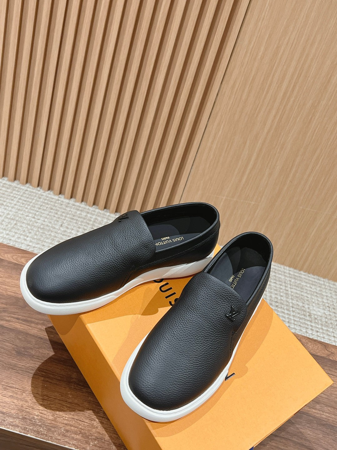 Black leather slip-on sneakers with white midsole, two pairs shown