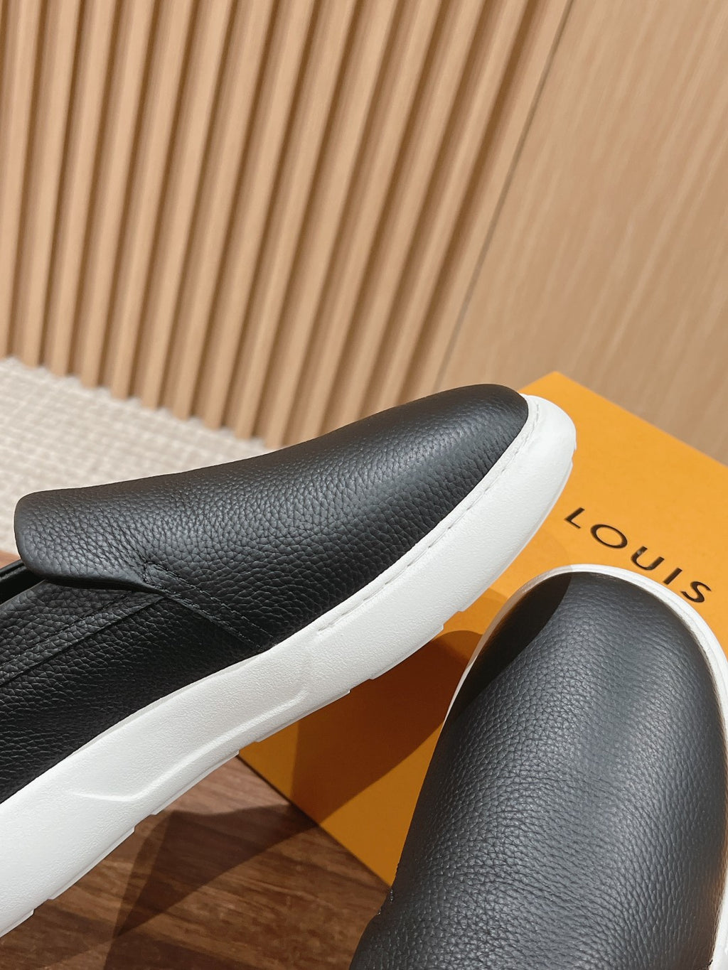 Black leather slip-on sneaker close-up with white rubber sole edge