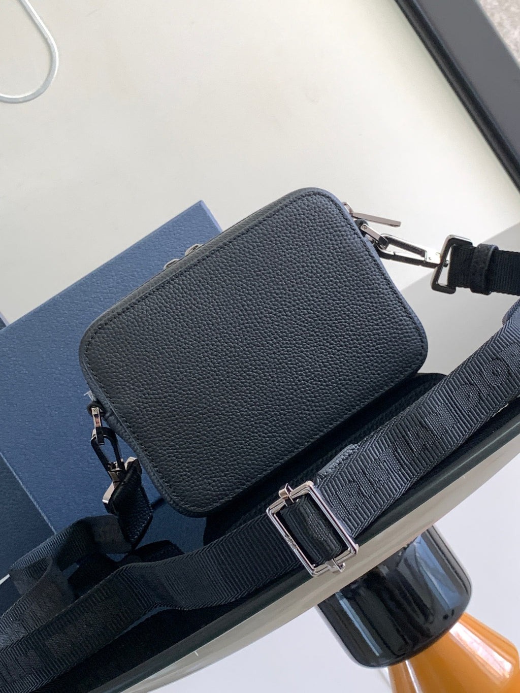 Small zip crossbody bag in textured dark blue leather with adjustable strap and metal clasp