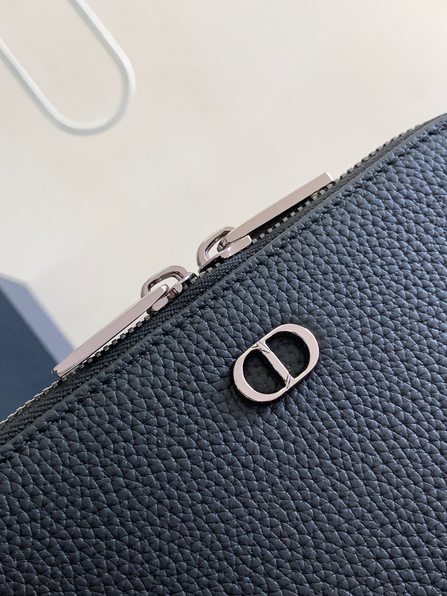 Textured dark blue leather pouch with silver-tone zipper and D logo accent