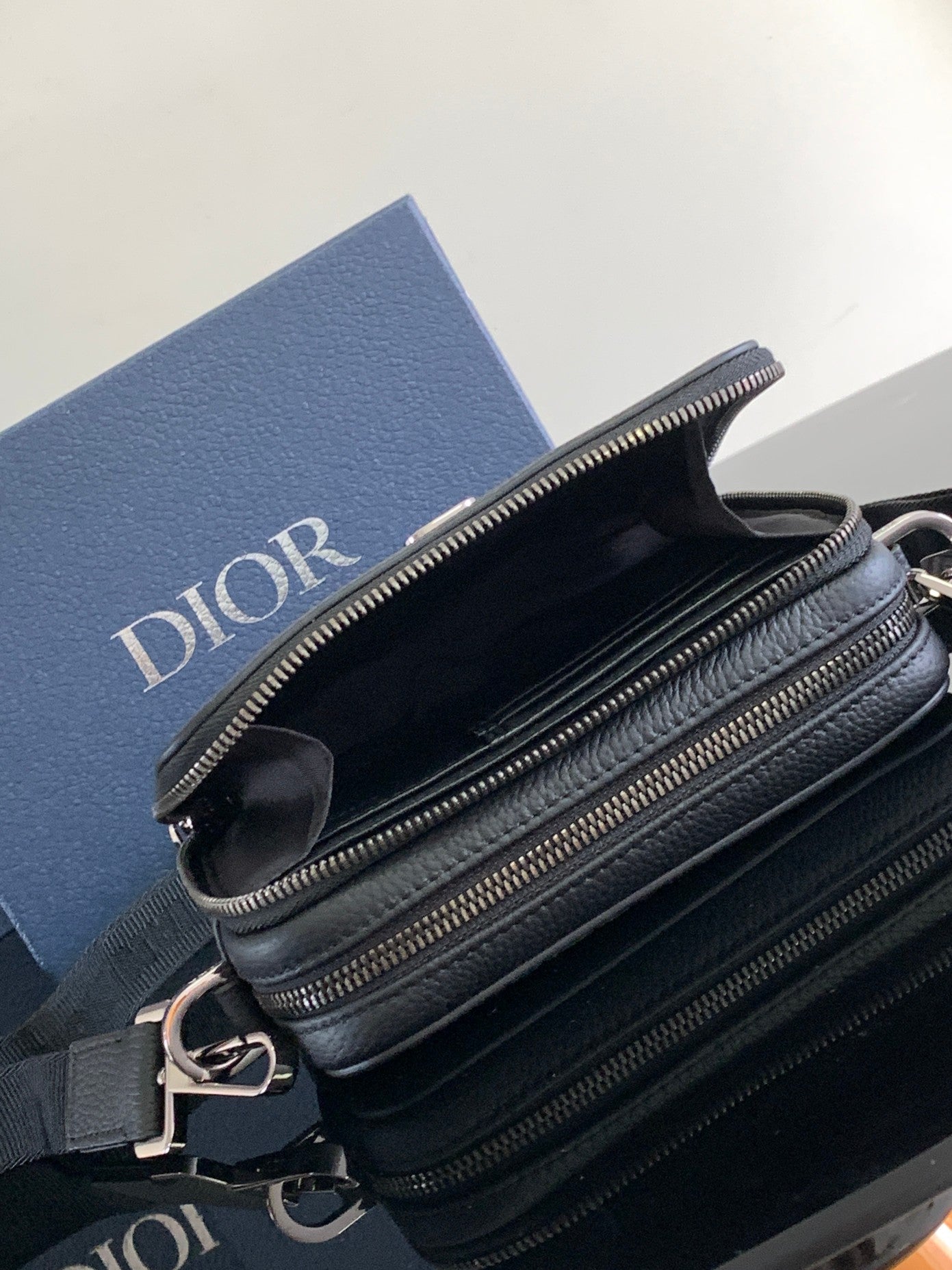 Double-compartment zip crossbody bag in textured dark blue leather with silver-tone hardware