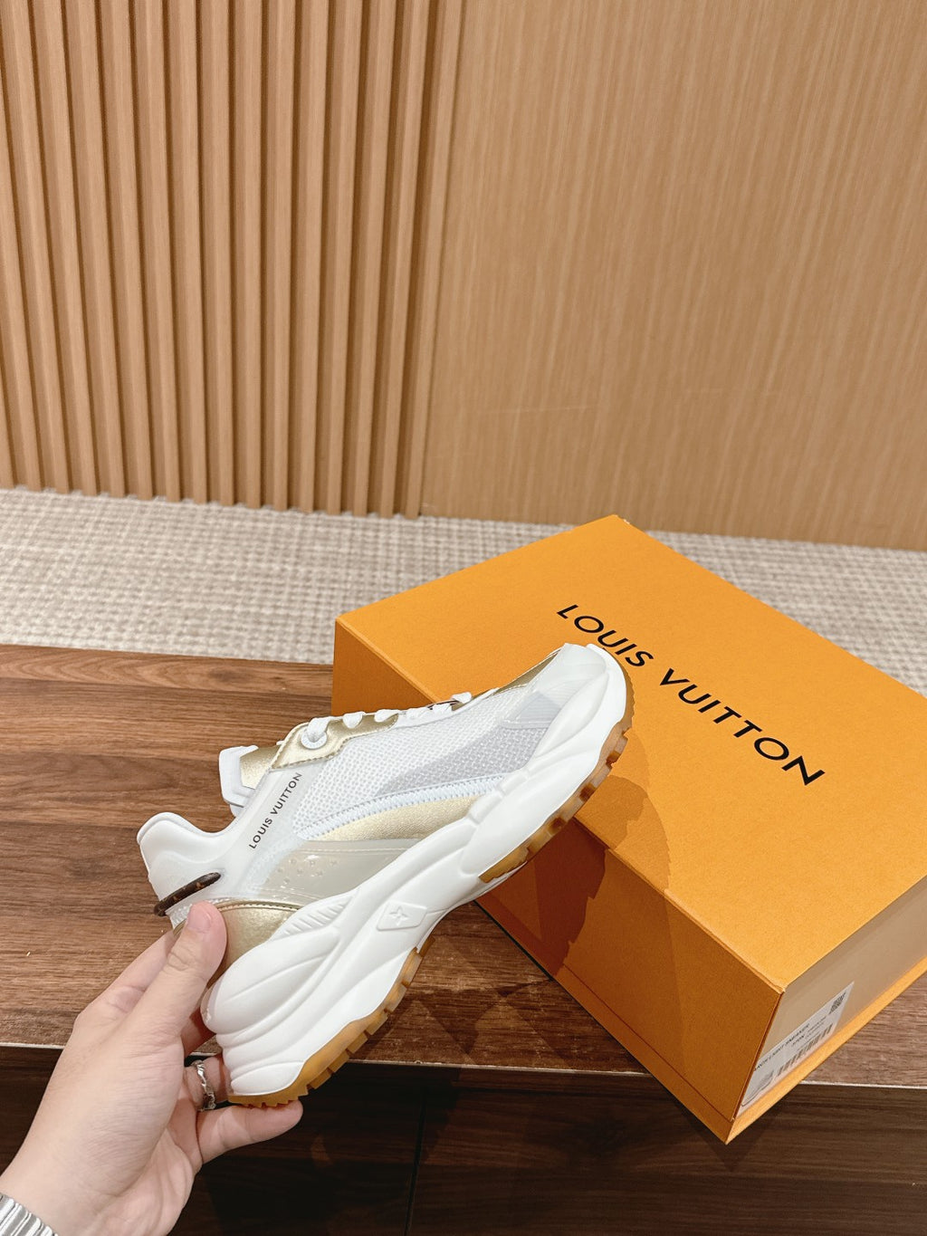 White Louis Vuitton unisex sneaker close-up, lace-up with gold logo patch